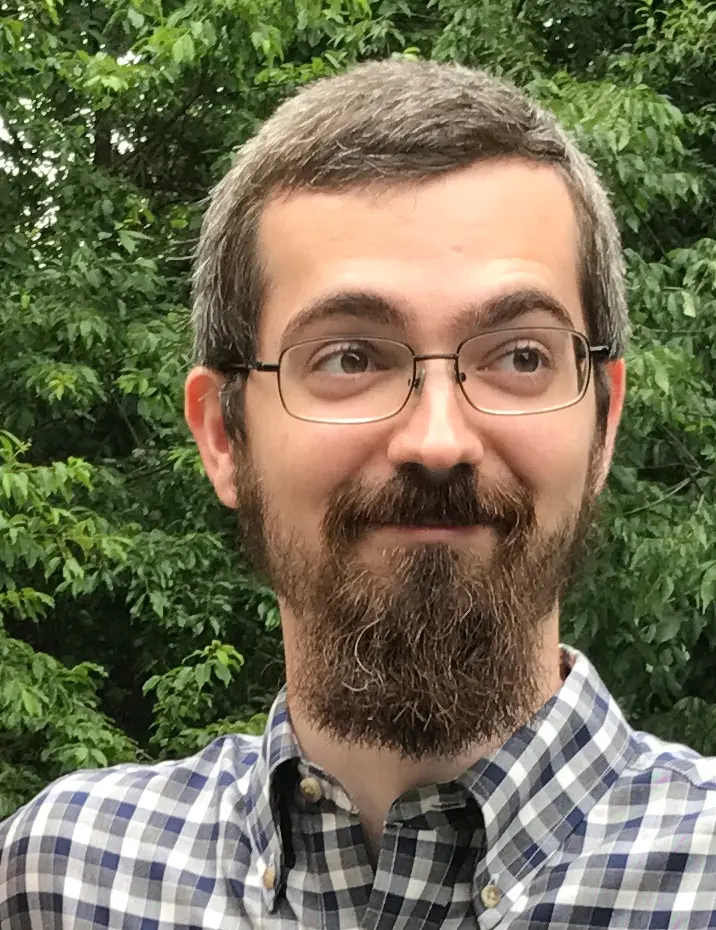 A photo of Miles Wheeler. He has a beard and wears glasses.